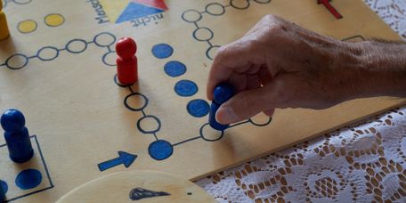 Eine Seniorin spielt Mensch ärger dich nicht