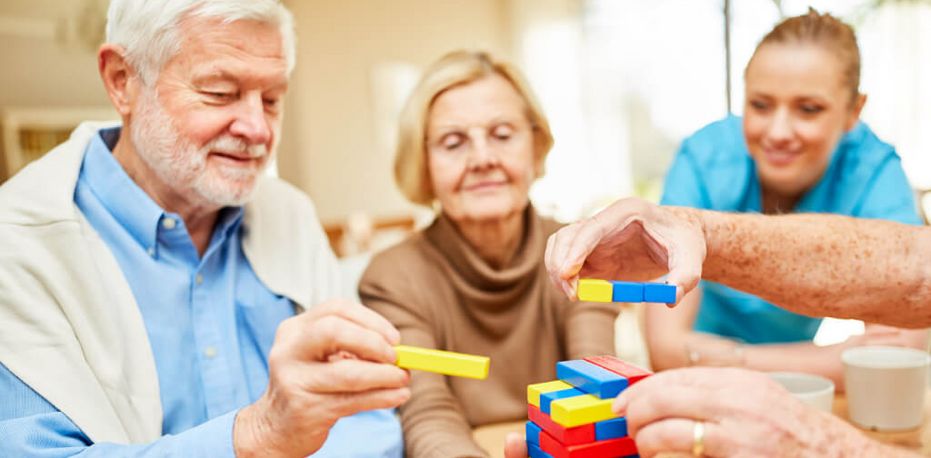 Seniorinnen und Pflegekraft spielen Jenga
